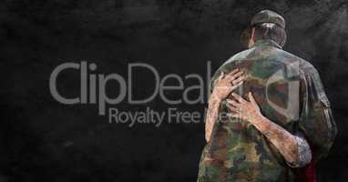 Back of soldier being hugged against black grunge background with overlay and flare