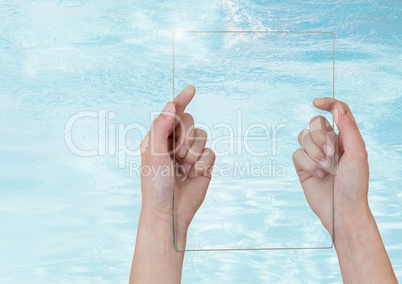 Hand holding glass screen over clear blue water