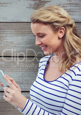 Smiling woman using tablet PC against wooden wall