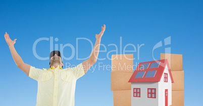 Delivery man with arms raised against house and parcels