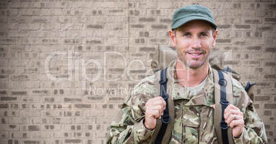Soldier with backpack against brown brick wall
