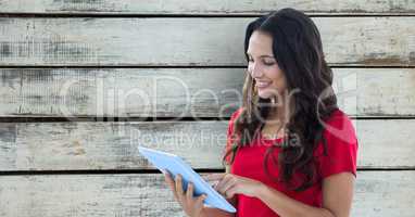 Smiling woman using digital tablet against wooden wall