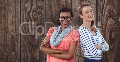 Portrait of confident businesswomen standing arms crossed against wooden wall