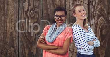 Portrait of confident businesswomen standing arms crossed against wooden wall