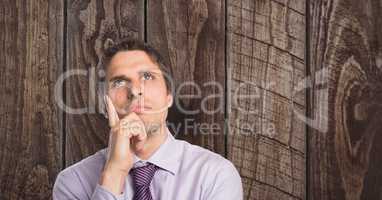 Thoughtful businessman with hands on chin against wooden wall