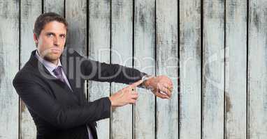 Portrait of angry businessman showing time on wristwatch against wooden wall