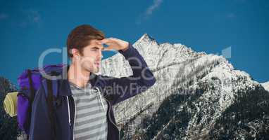 Male traveler shielding eyes while carrying backpack on mountain