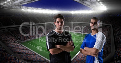 Confident soccer players with arms crossed against stadium