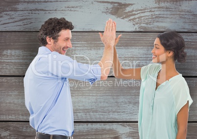 Happy business people giving high-five against wooden wall