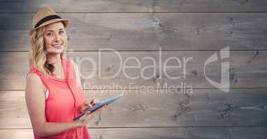 Young woman holding tablet PC against wooden wall