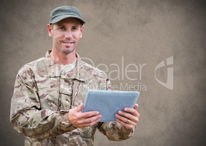 Soldier with tablet against brown background with grunge overlay