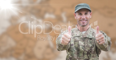 Soldier thumbs up against blurry brown map with flare