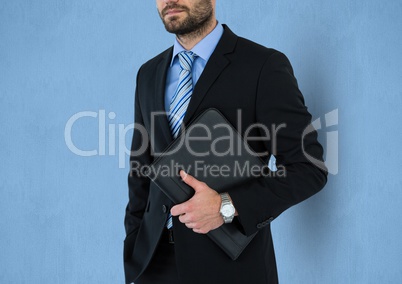 Midsection of businessman holding folder against blue background