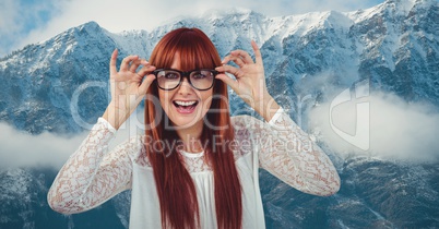 Happy redhead woman wearing eyeglasses against snowcapped mountains