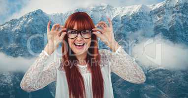 Happy redhead woman wearing eyeglasses against snowcapped mountains