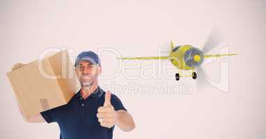 Delivery man carrying parcel while showing thumbs up against airplane