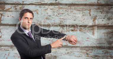 Portrait of businessman showing time on wristwatch against wooden wall