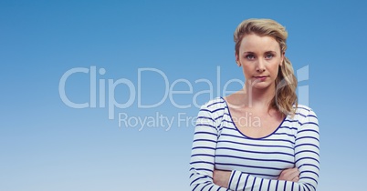 Confident woman with arms crossed against clear blue sky