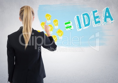 Back of business woman pointing at lightbulb doodle against white wall