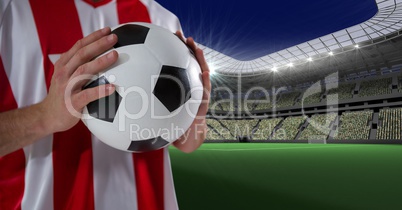 Midsection of player holding soccer ball on field