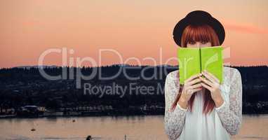 Female hipster holding book at lake shore