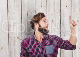 Male hipster pointing upwards against wooden wall