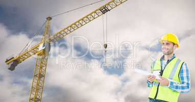 Smiling architect holding blueprint against crane