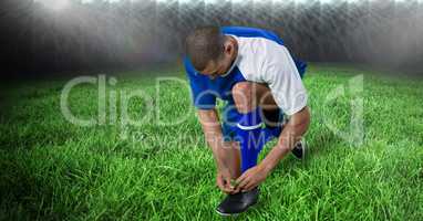 Soccer player tying shoelace on field