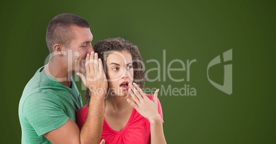 Businessman whispering in shocked colleague's ear against green background