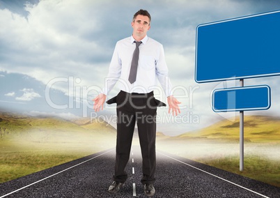 Businessman with empty pockets standing on road by blank signs