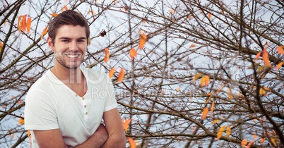 Confident hipster smiling against autumn trees