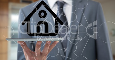 Midsection of businessman with house on device