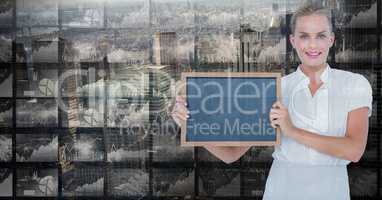 Smiling businesswoman holding blank slate against screens