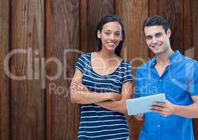 Portrait of confident couple with digital tablet against wooden wall