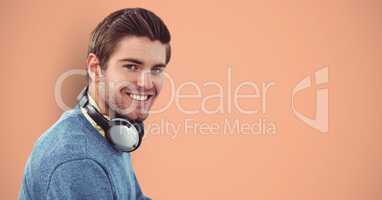 Smiling male hipster with headphones against orange background