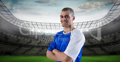 Smiling soccer player with arms crossed at stadium