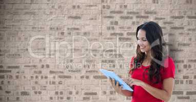 Smiling woman holding tablet PC against wall