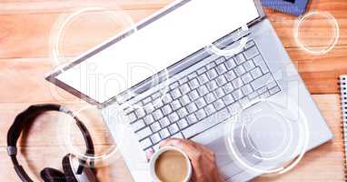 Hand holding coffee cup over laptop