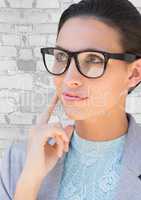Close up of business woman in glasses thinking against white brick wall