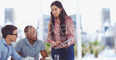 Businesswoman showing data on digital tablet to colleagues