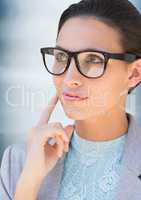 Close up of business woman in glasses thinking against blurry blue background