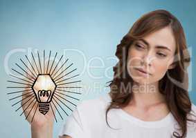 Woman drawing lightbulb doodle with flare against blue background