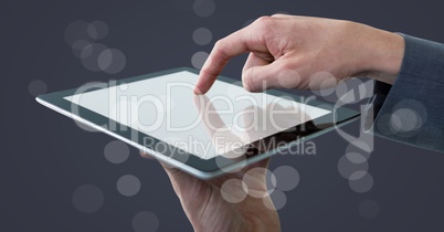 Hands touching tablet behind bokeh against grey background