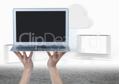 Hands holding laptop against blurry screens