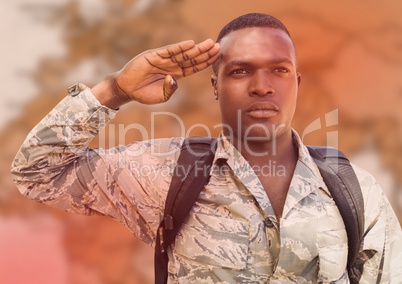 Soldier with backpack saluting against blurry brown map and red overlay