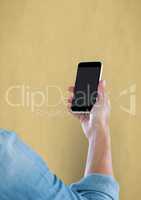 Close-up of hand holding smart phone with blank screen over beige background