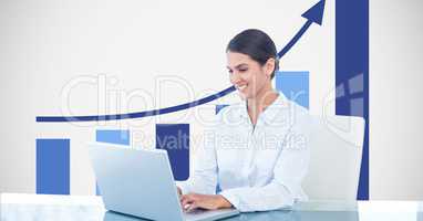 Smiling businesswoman using laptop against graph