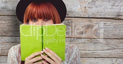 Redhead woman covering face with book