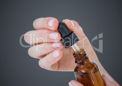 Hand with dropper and bottle against grey background