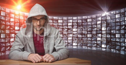 Male hacker wearing hooded shirt against screens
